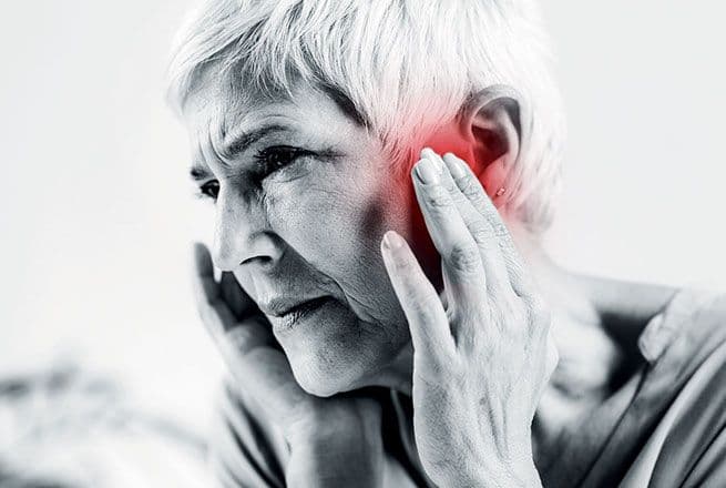 Une femme porte ses mains à ses oreilles à cause de nuisances.