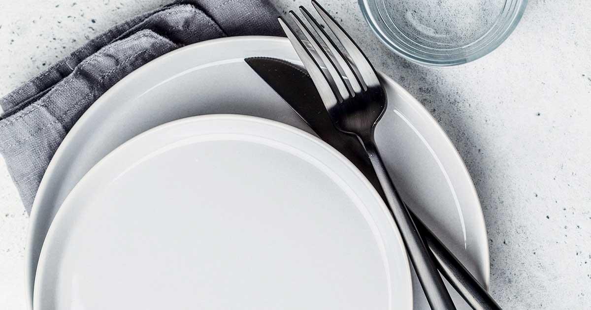 Assiette et plats vides disposés sur une table.